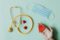 Top view of crop anonymous person hand with red paper heart on table with stethoscope and medical mask for coronavirus prevention